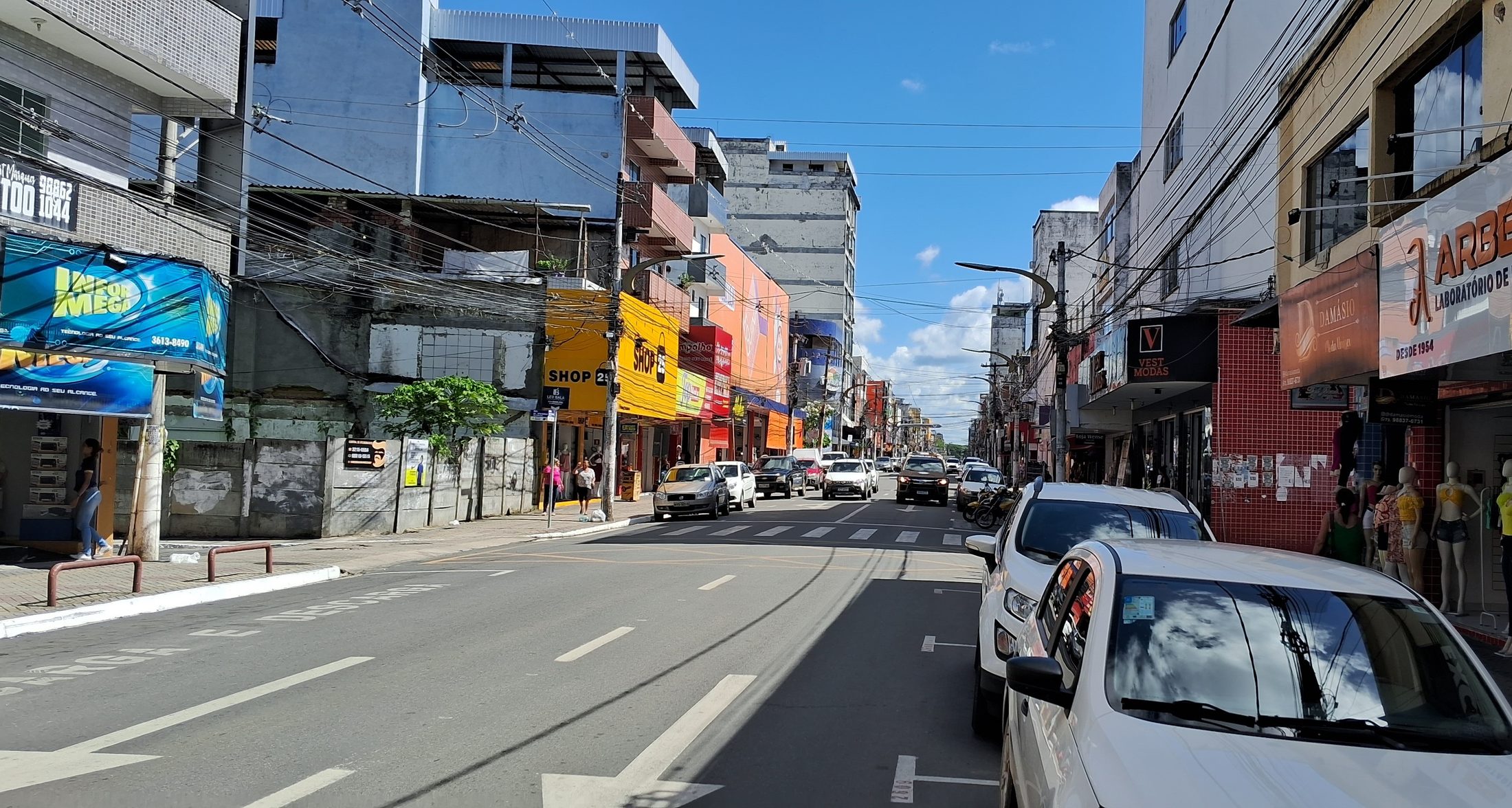 Rua comercial no centro de Itabuna, com lojas, pedestres e trânsito